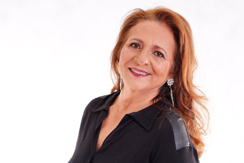 Portrait of a smiling senior woman with long hair and earrings in a black outfit.